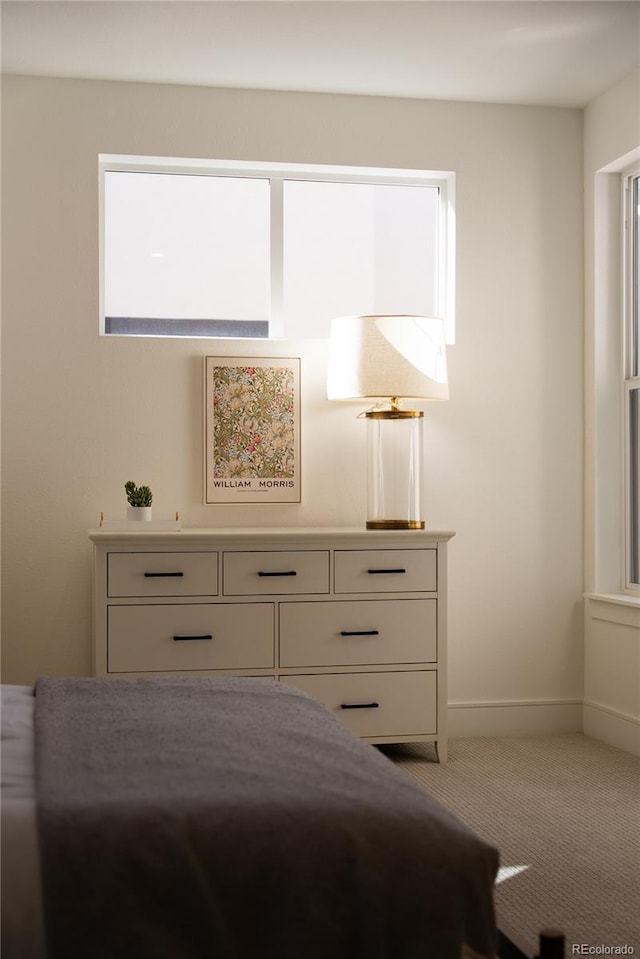 bedroom with light colored carpet and baseboards