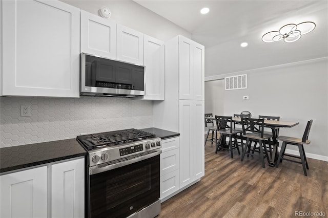 kitchen with stainless steel appliances, backsplash, dark countertops, and visible vents