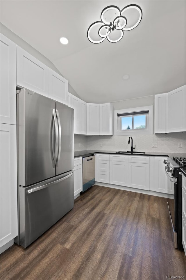 kitchen with a sink, lofted ceiling, stainless steel appliances, dark wood finished floors, and white cabinets