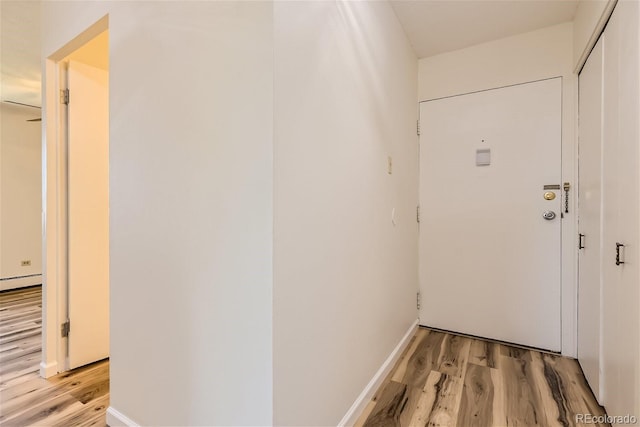 corridor featuring a baseboard radiator and light hardwood / wood-style floors