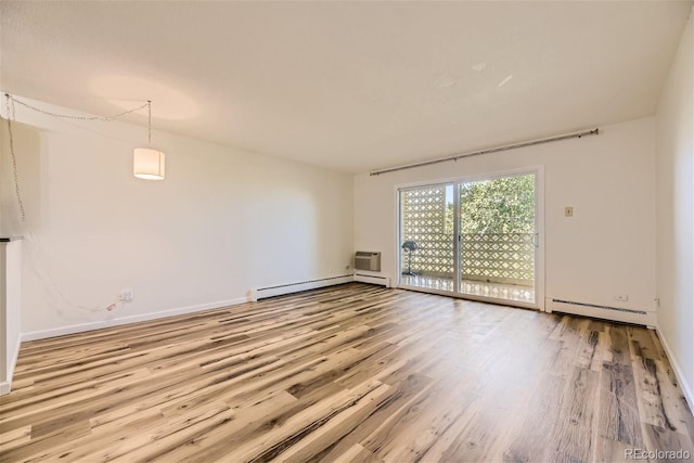 spare room featuring baseboard heating, wood-type flooring, and an AC wall unit