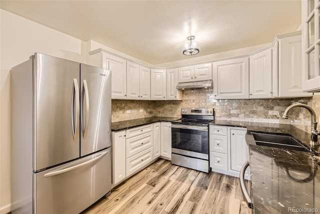 kitchen featuring light hardwood / wood-style floors, sink, white cabinetry, stainless steel appliances, and dark stone counters