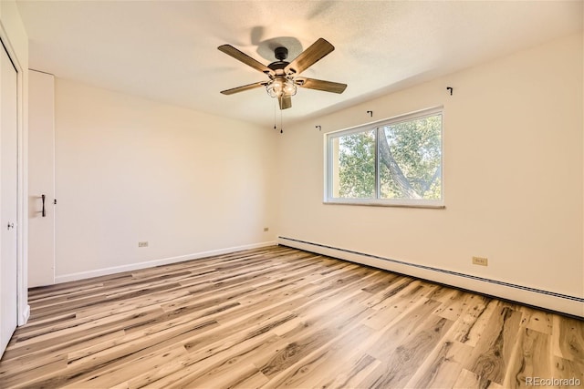 spare room featuring baseboard heating, light hardwood / wood-style floors, and ceiling fan