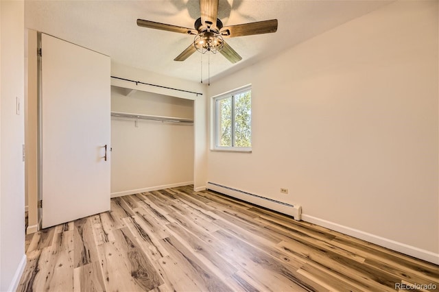 unfurnished bedroom with ceiling fan, a closet, baseboard heating, and light hardwood / wood-style floors