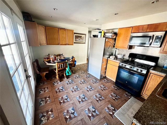 kitchen featuring tasteful backsplash, black range with gas cooktop, white fridge, and a healthy amount of sunlight