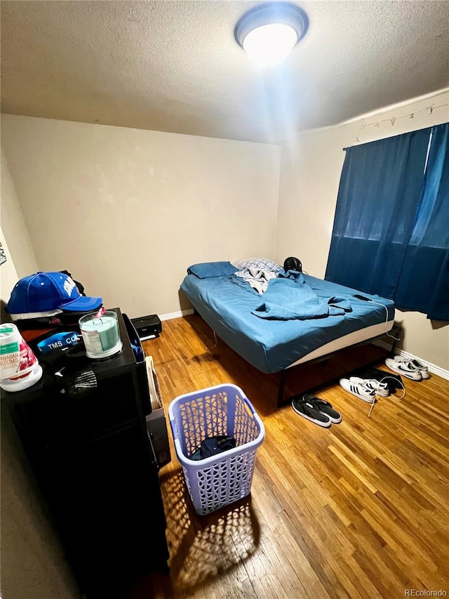 bedroom with hardwood / wood-style floors and a textured ceiling