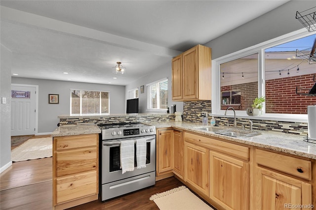 kitchen with sink, light brown cabinets, stainless steel range with gas stovetop, kitchen peninsula, and light stone countertops