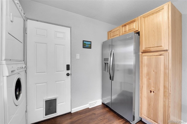 laundry area with stacked washer / dryer, dark wood-type flooring, a textured ceiling, and cabinets