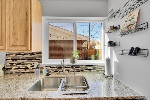 kitchen with light stone counters, sink, decorative backsplash, and light brown cabinets