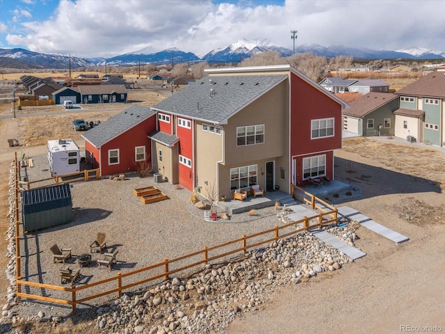 view of front of home with a patio area, a residential view, fence, and a mountain view