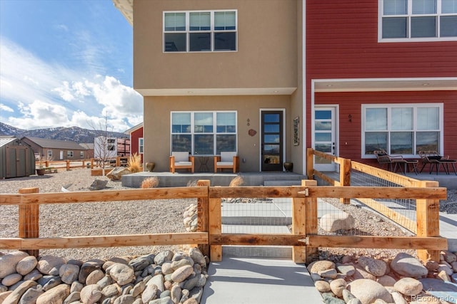 exterior space with a fenced front yard, a mountain view, and stucco siding