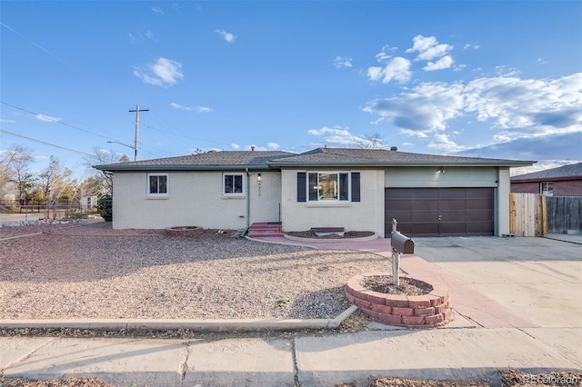 ranch-style home featuring an attached garage, fence, concrete driveway, and brick siding