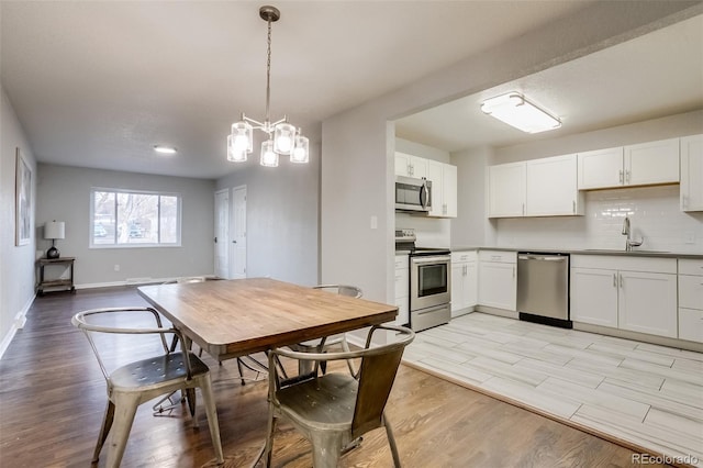 kitchen with stainless steel appliances, light wood finished floors, a sink, and tasteful backsplash