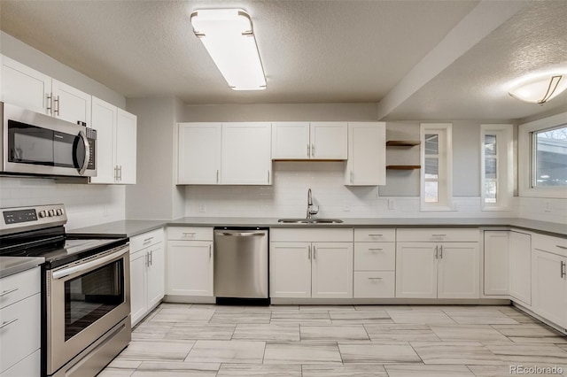 kitchen with open shelves, decorative backsplash, appliances with stainless steel finishes, white cabinets, and a sink