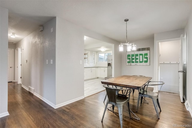 dining room with visible vents, a notable chandelier, baseboards, and wood finished floors