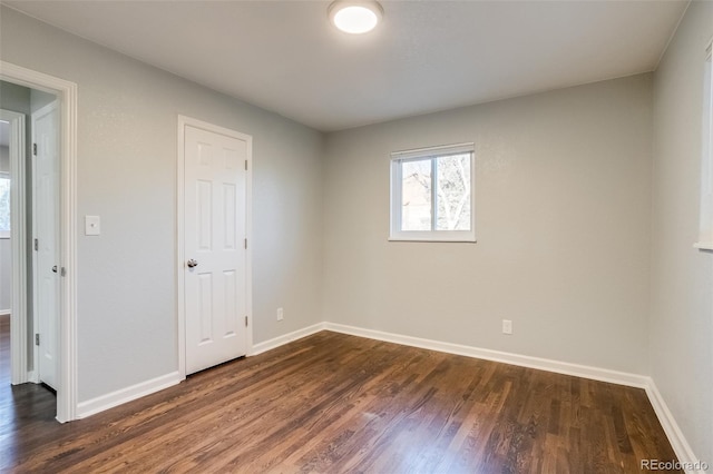 empty room with dark wood finished floors and baseboards