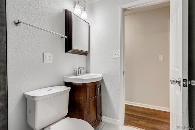 bathroom featuring toilet, baseboards, and vanity