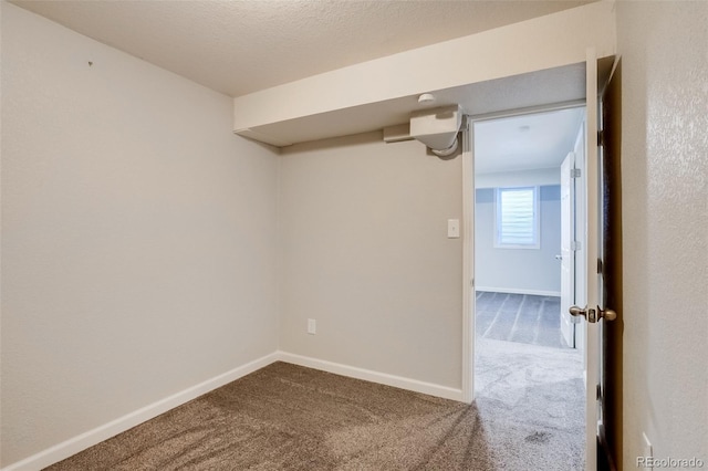 unfurnished room with a textured ceiling, carpet floors, and baseboards