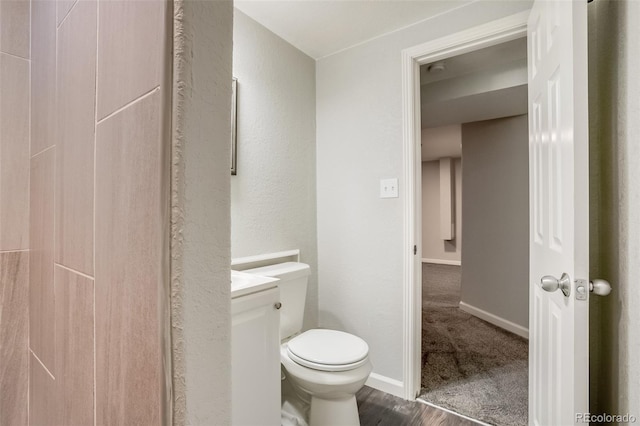 bathroom featuring baseboards, vanity, toilet, and wood finished floors