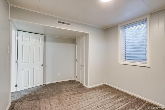 empty room with carpet, visible vents, and baseboards