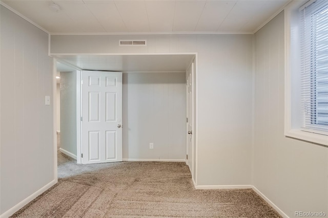 interior space with a wealth of natural light, carpet, visible vents, and ornamental molding