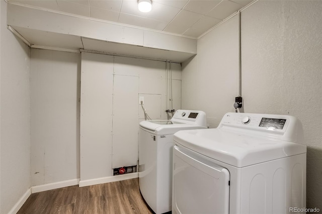 washroom featuring laundry area, baseboards, washer and clothes dryer, and wood finished floors