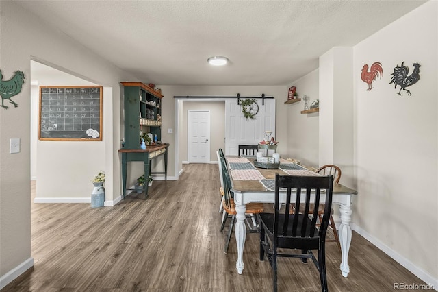 1775 Longbranch St, Strasburg, CO 80136 - dining room featuring a barn door, wood finished floors, and a textured ceiling