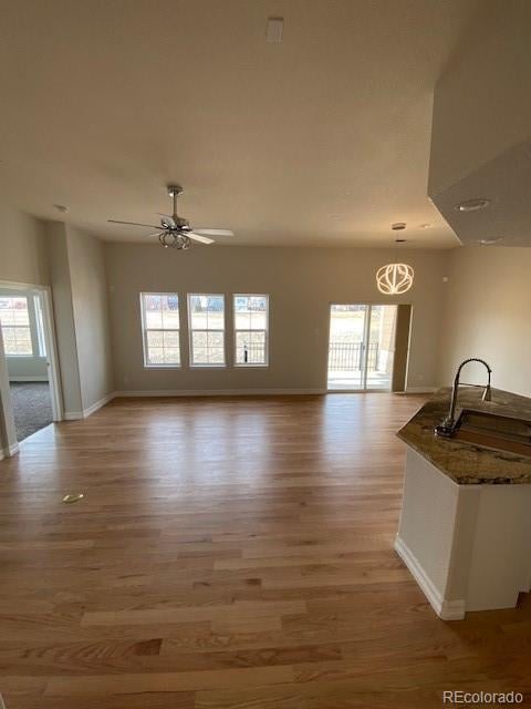 unfurnished living room featuring plenty of natural light, ceiling fan, and light wood-type flooring