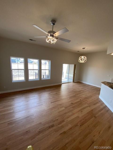 unfurnished living room featuring dark wood-type flooring, a wealth of natural light, and ceiling fan