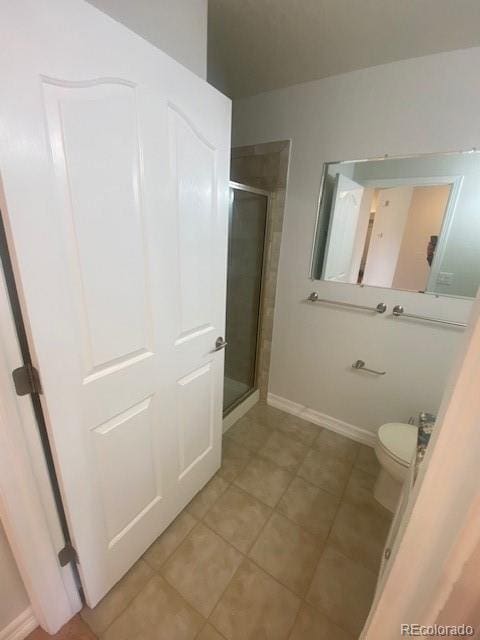 bathroom featuring tile patterned flooring, a shower with shower door, and toilet