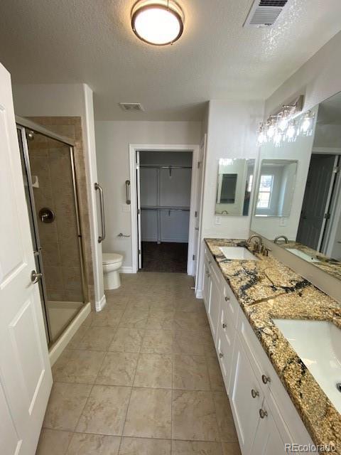 bathroom with an enclosed shower, a textured ceiling, and toilet