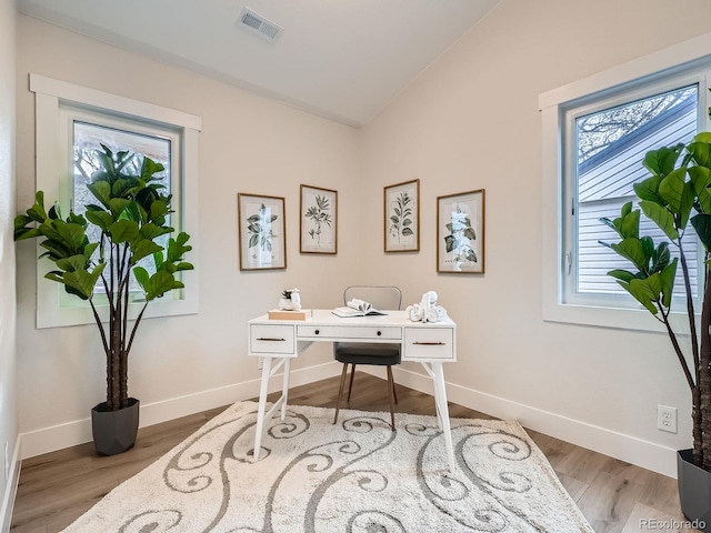 home office with visible vents, lofted ceiling, baseboards, and wood finished floors