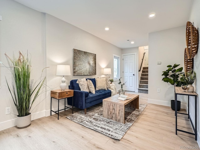 living area with recessed lighting, baseboards, light wood-style flooring, and stairs