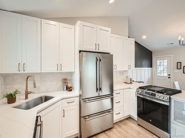 kitchen with a sink, lofted ceiling, appliances with stainless steel finishes, and white cabinets