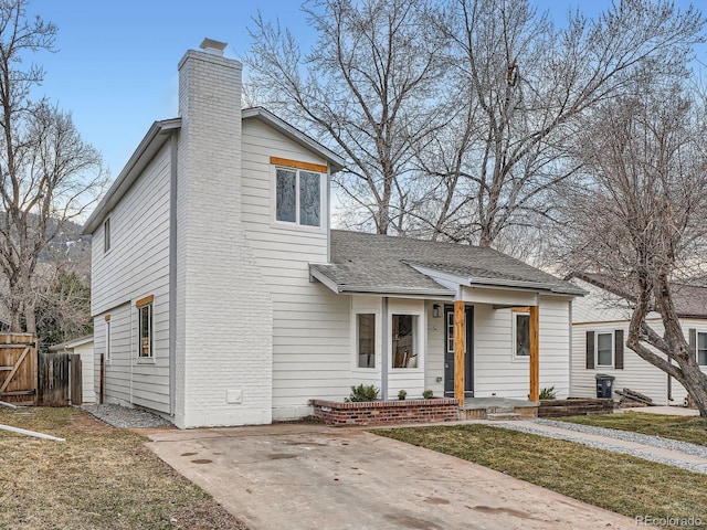 view of front of home featuring a front yard, a shingled roof, a chimney, and fence