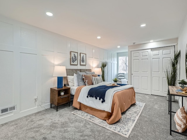 bedroom with a decorative wall, visible vents, and carpet