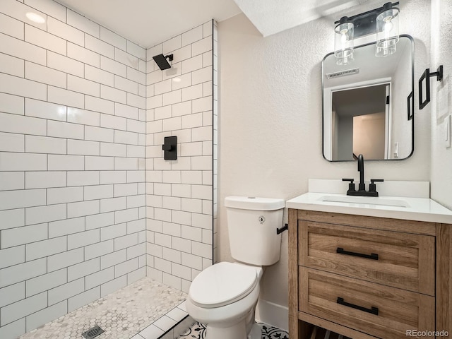 full bathroom with vanity, toilet, visible vents, and tiled shower