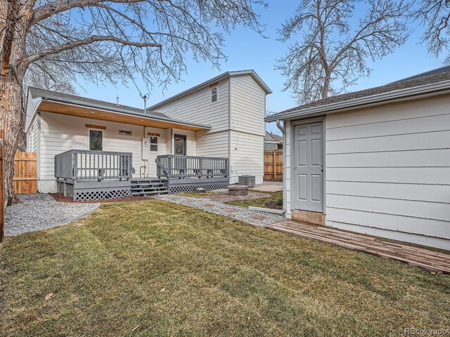 rear view of property featuring a deck, central air condition unit, a yard, and fence