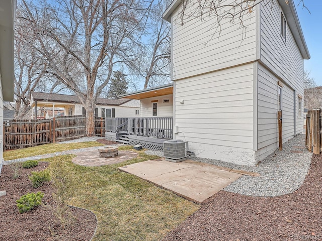 rear view of property with a fenced backyard, a yard, a fire pit, central AC unit, and a patio area