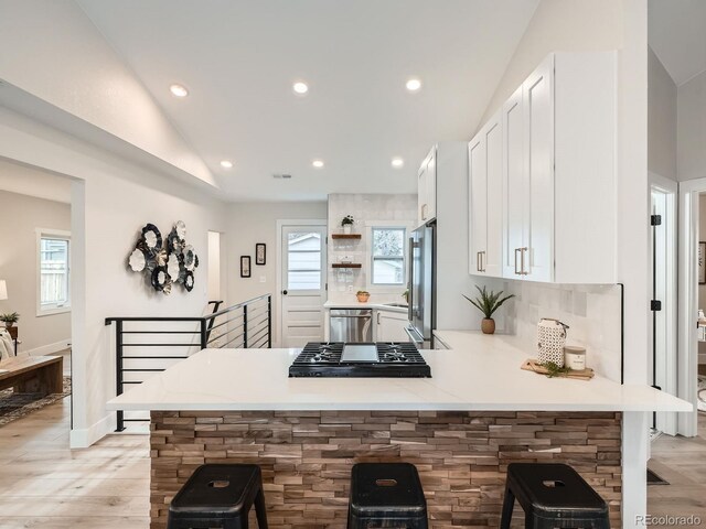 kitchen with a wealth of natural light, a peninsula, stainless steel appliances, and lofted ceiling