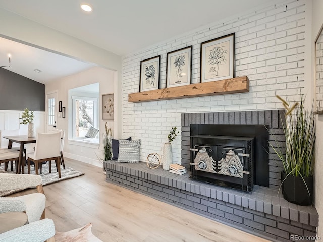 living room with a brick fireplace, a wainscoted wall, lofted ceiling, recessed lighting, and wood finished floors