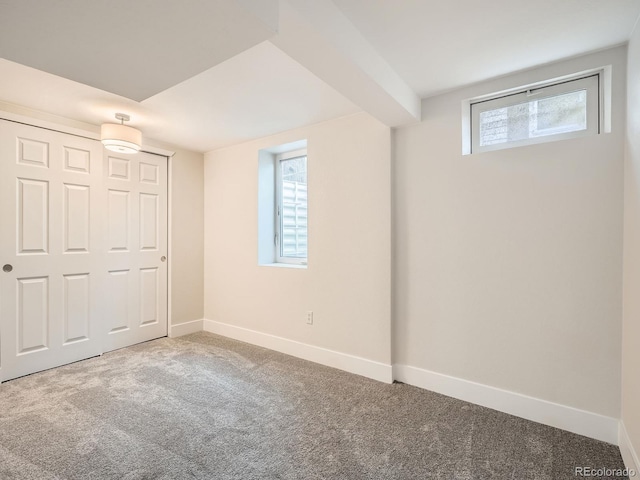 basement featuring carpet, baseboards, and a healthy amount of sunlight