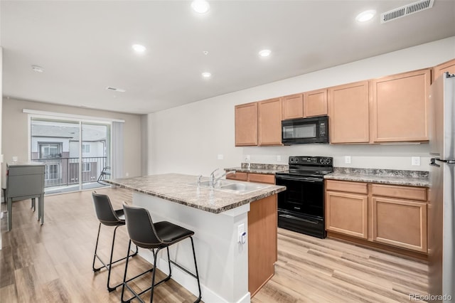 kitchen featuring an island with sink, sink, light hardwood / wood-style flooring, and black appliances