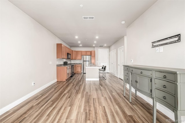 kitchen featuring a kitchen bar, light wood-type flooring, a kitchen island, and black appliances