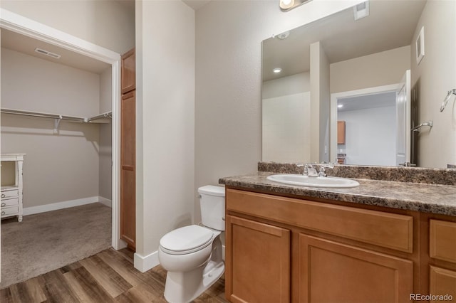 bathroom with wood-type flooring, vanity, and toilet