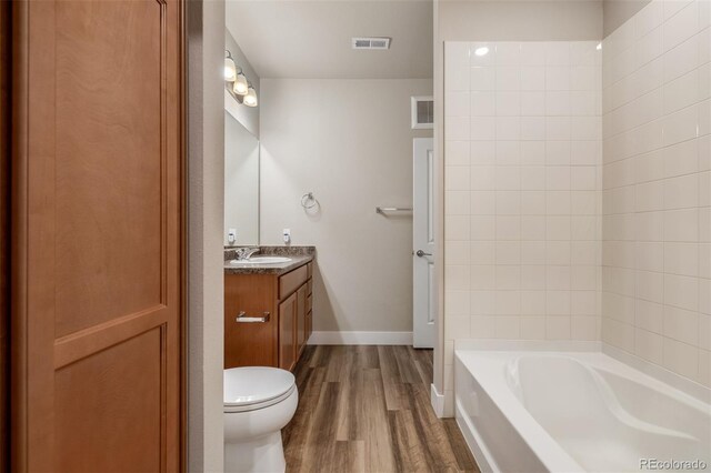 full bathroom with vanity, wood-type flooring, toilet, and washtub / shower combination