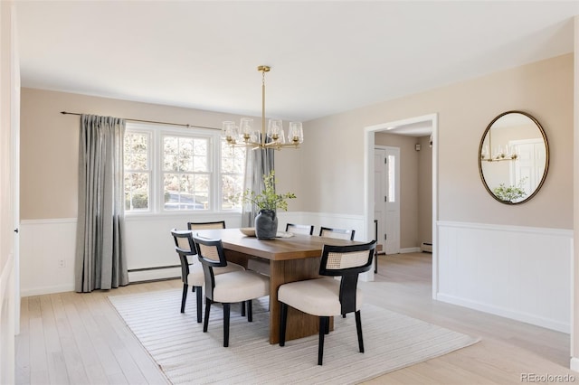 dining room featuring light wood-type flooring, a baseboard heating unit, and a notable chandelier