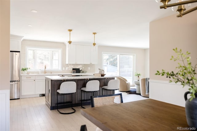 kitchen with decorative light fixtures, a kitchen island, and white cabinetry