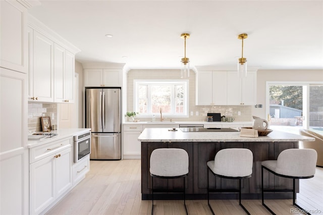 kitchen with pendant lighting, a kitchen island, white cabinetry, and stainless steel refrigerator