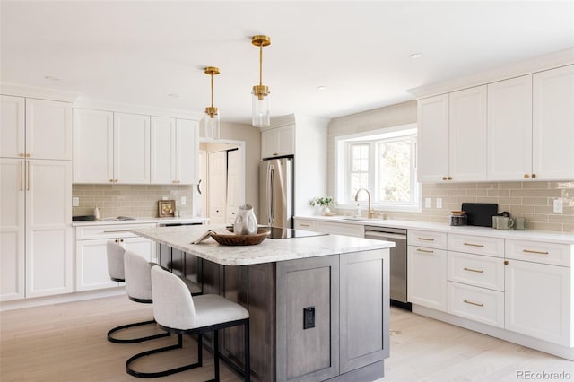 kitchen featuring pendant lighting, a kitchen island, white cabinetry, and stainless steel appliances